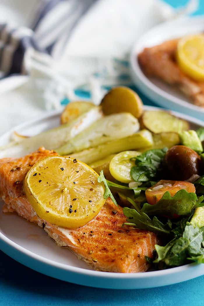 Tender and flavorful baked salmon fillet with lemon served with a delicious arugula avocado salad. This baked salmon fillet recipe is baked in a sheet pan. 