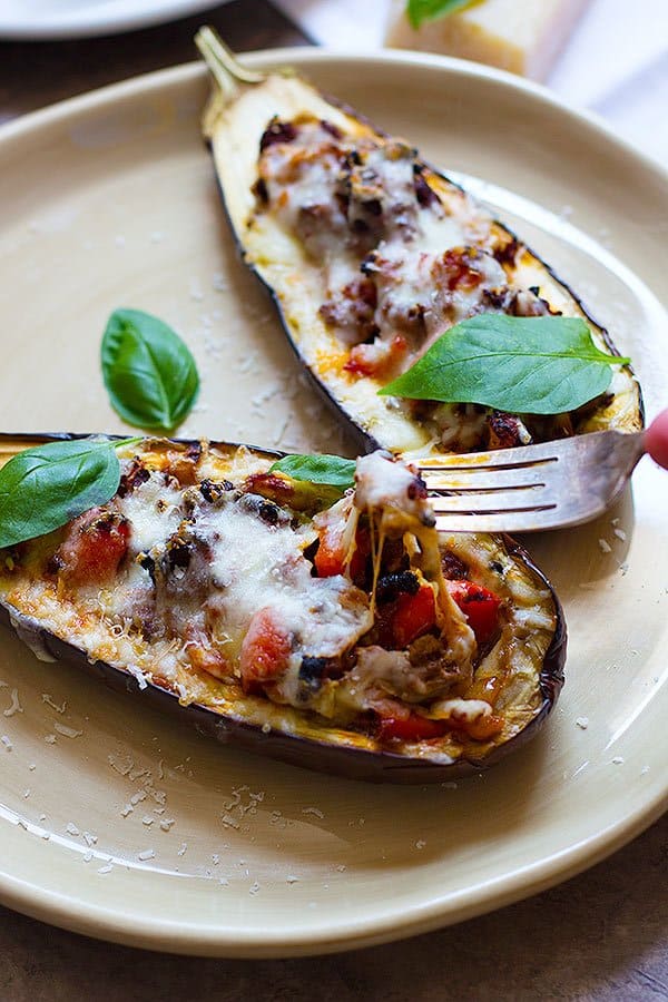 Close-up of fork digging into stuffed eggplants with parmesan and basil