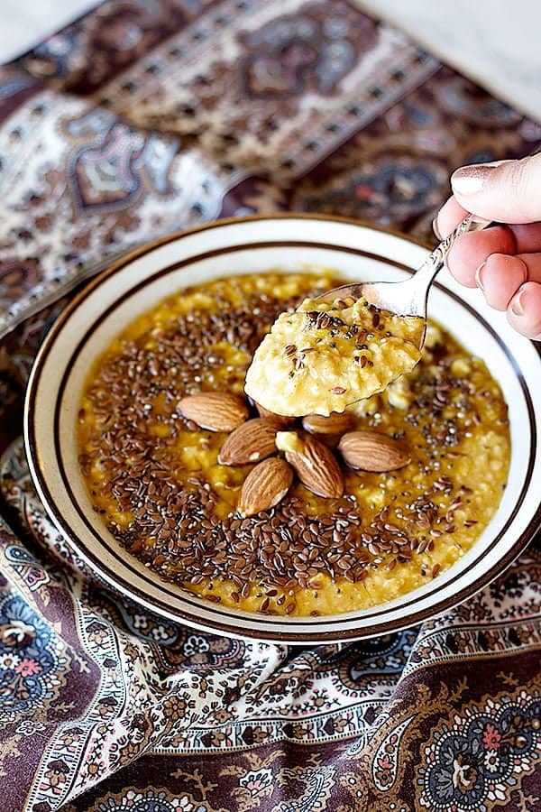 Easy pumpkin spice oatmeal topped with chia seeds and flax seed with whole almonds. 