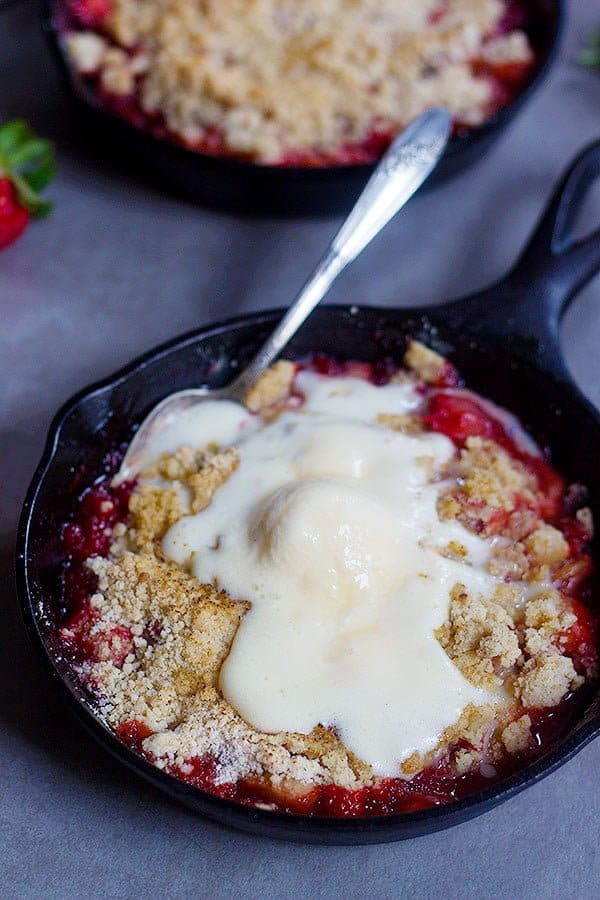 Strawberry Rhubarb Crumble served with vanilla ice cream in a small cast iron skillet. 
