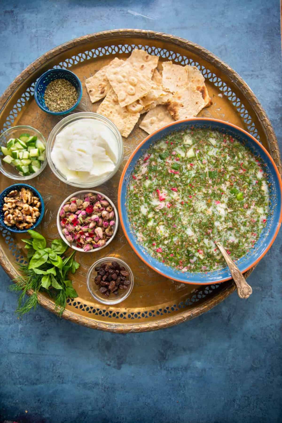 A large bowl of abdoogh khiar on a golden tray with other ingredients. 
