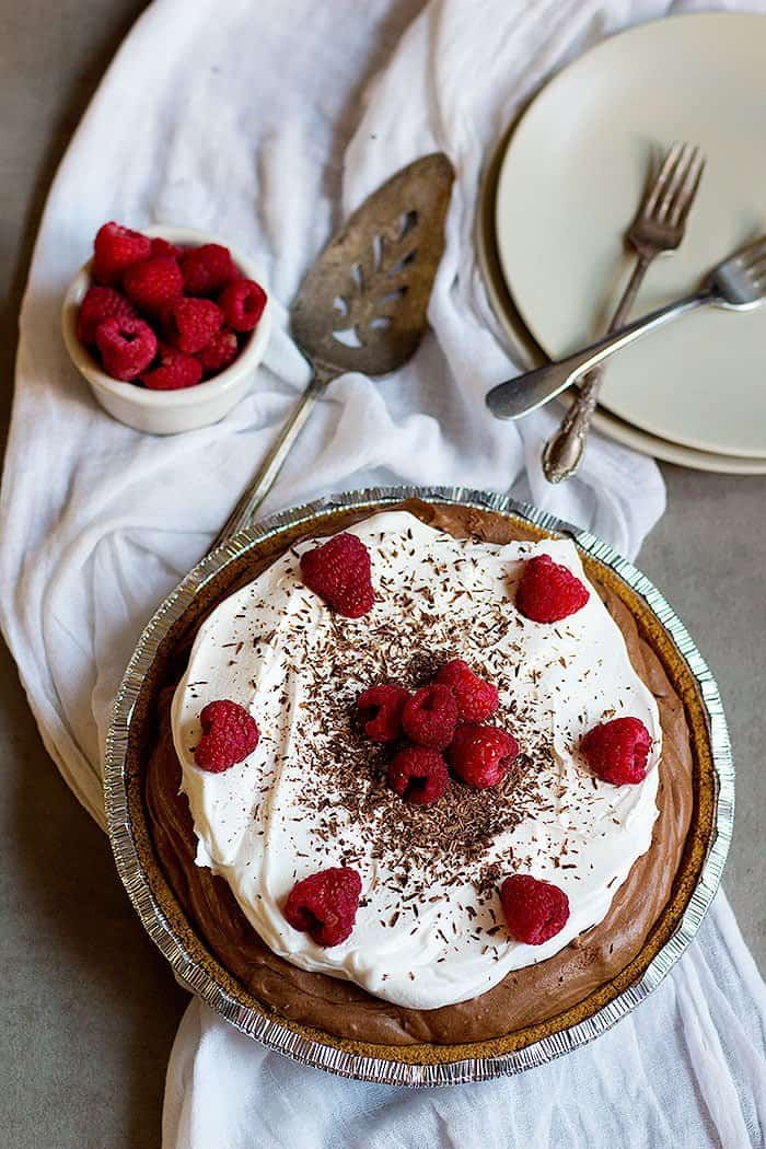 no bake chocolate cream pie topped with whipped cream and raspberries