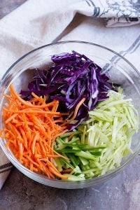 Asian slaw made of shredded white and purple cabbage, shredded carrots and cucumbers. Mix all together in a large bowl. 