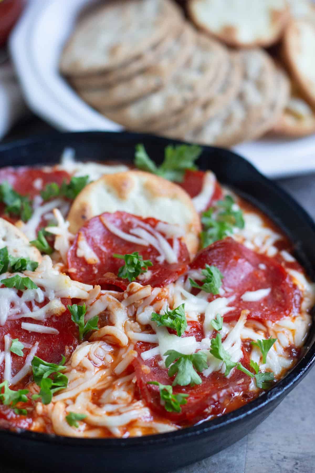 Pepperoni pizza dip topped with parsley and mozzarella cheese. 