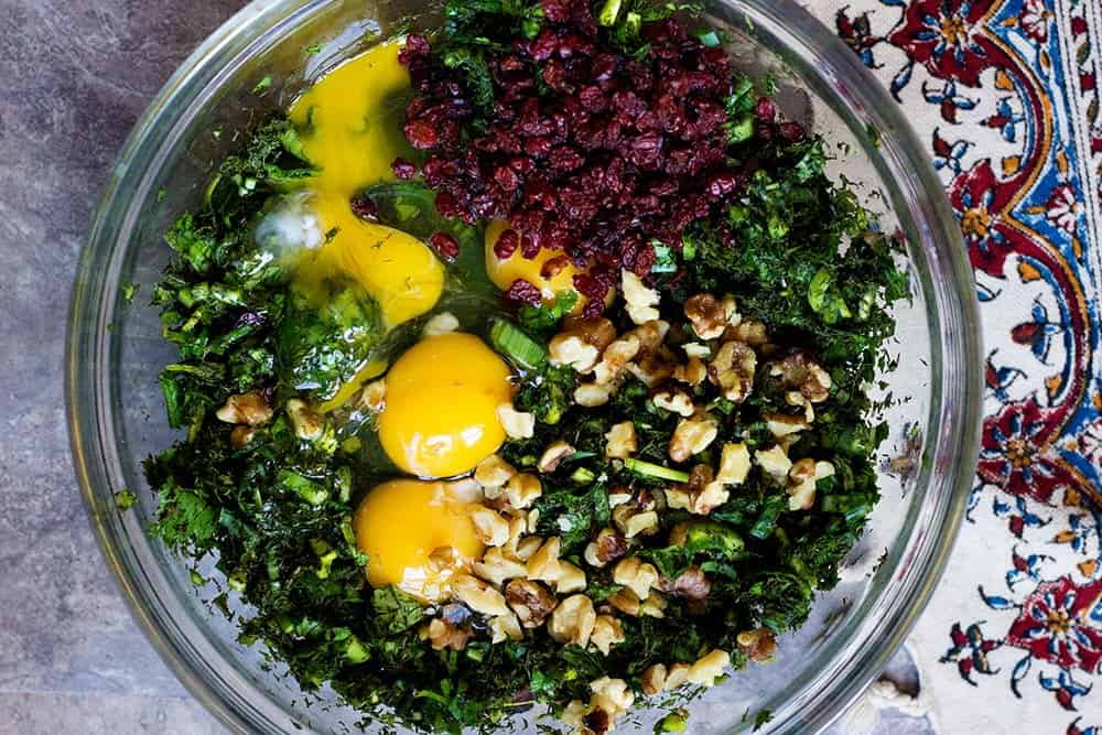 Mix all chopped herbs with eggs, walnuts and barberries. This will be the batter of kuku sabzi.