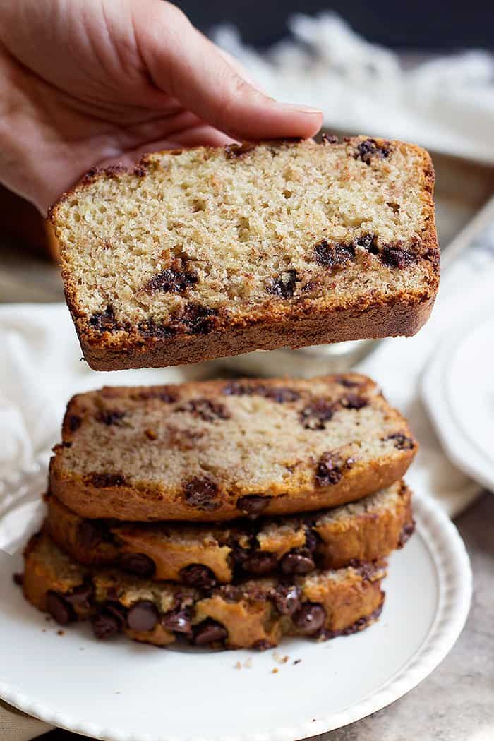 A slice of moist chocolate chip banana bread on top of a stack of moist chocolate chip banana bread slices