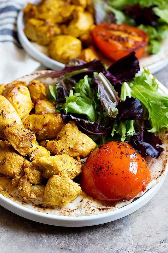 Servir le kebab persan avec de la tomate grillée, de la salade et du pain pita.