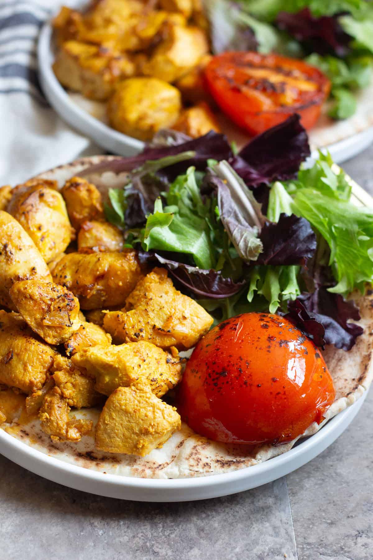 Close up shot of grilled saffron chicken kabobs and grilled tomatoes. 