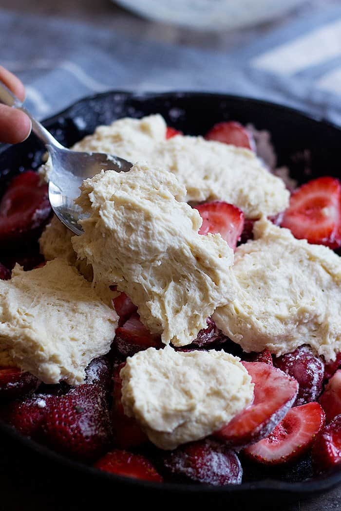 To make easy strawberry cobbler mix strawberries with sugar and cornstarch and then top them with a thick batter. 