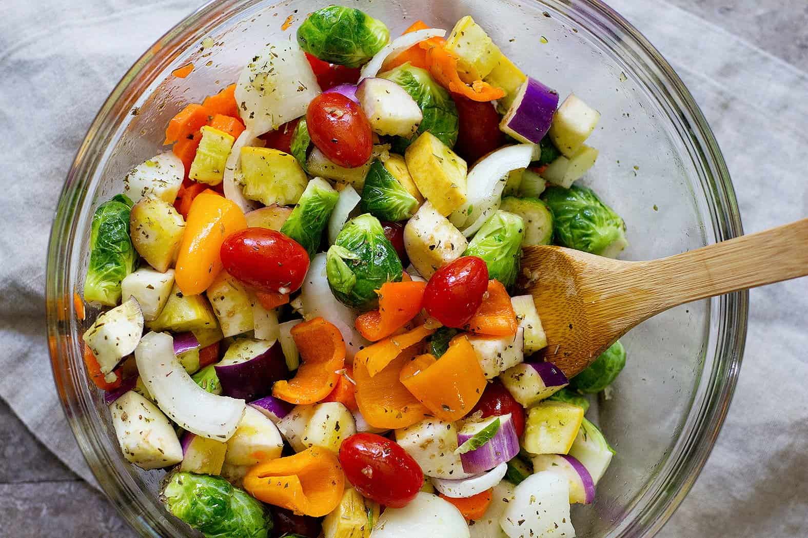 Chop all the vegetables and mix them with olive oil and spices in a large bowl. 