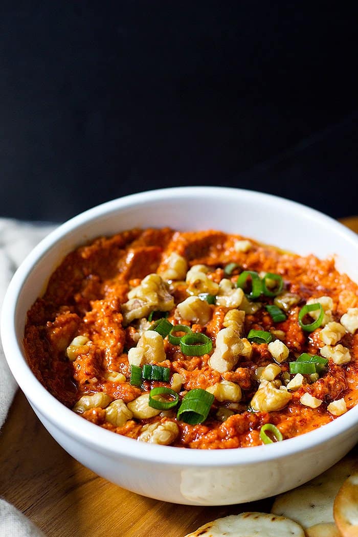 Top roasted red pepper and walnut dip with walnuts and green onions. 