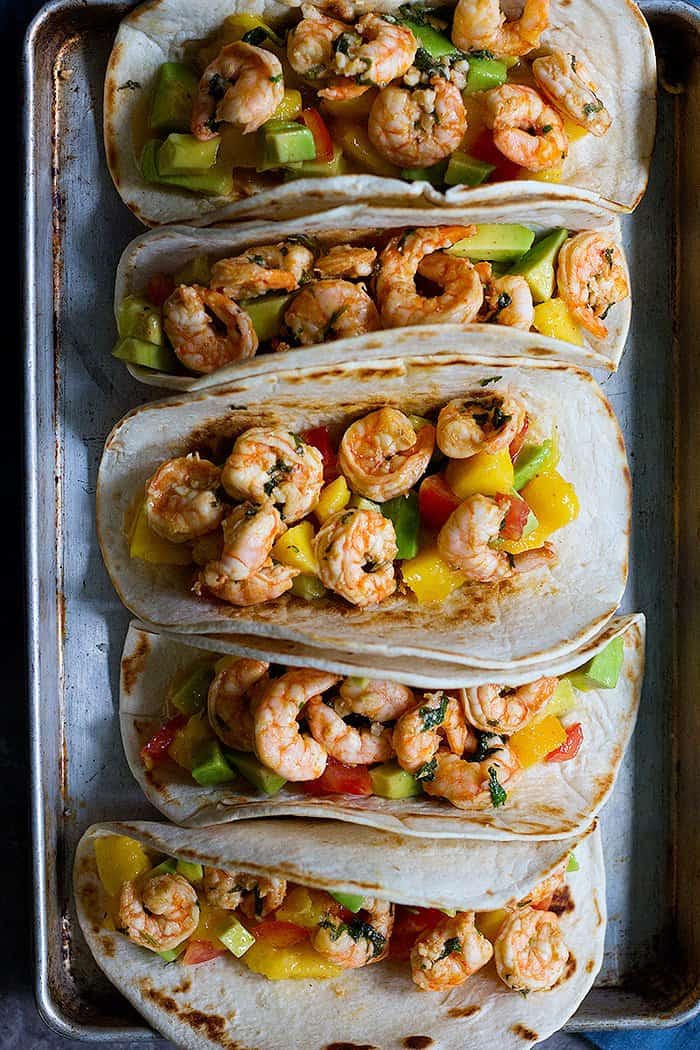 Spicy shrimp tacos with avocado mango salsa make a delicious weeknight dinner. The shrimps are flavored with a spicy marinade and are served with a sweet and savory salsa for balance.