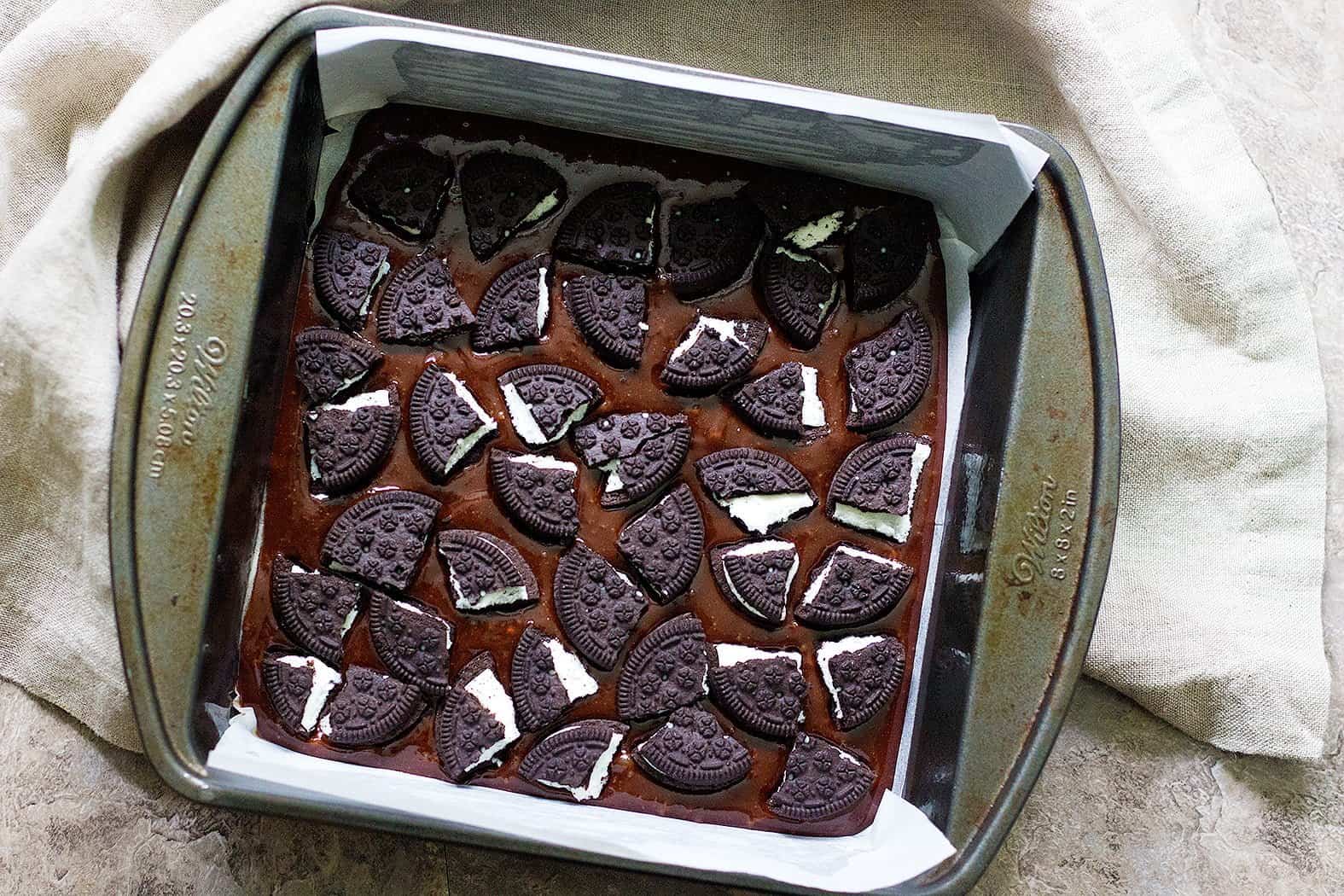 Pour half of the brownie batter into the prepared pan and layer half of the oreo pieces on top. 