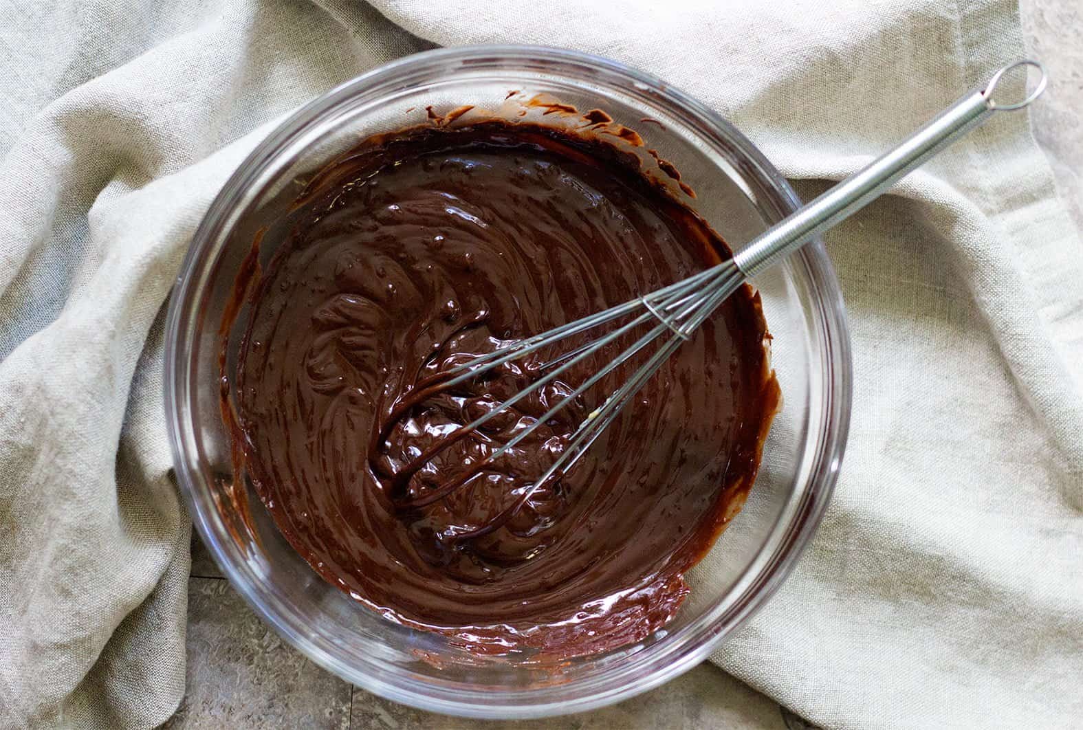 To start making oreo brownies, melt chocolate and butter in a microwave safe bowl. 