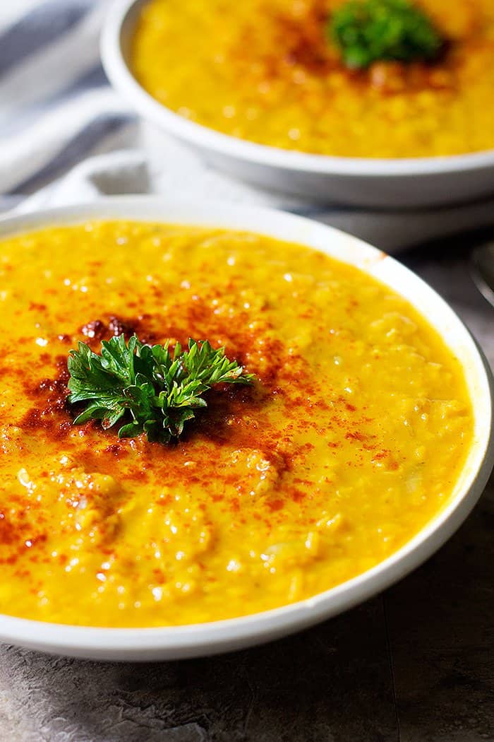 This turmeric red lentil soup is topped with paprika and parsley. 