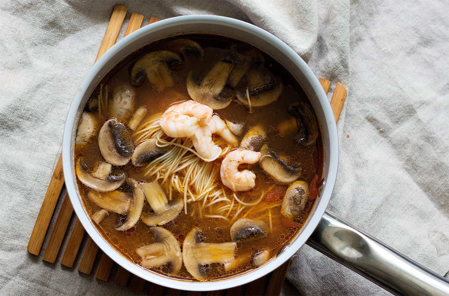 Add in shrimp, noodles and mushrooms to the spicy ramen soup and cook for about 5 minutes.