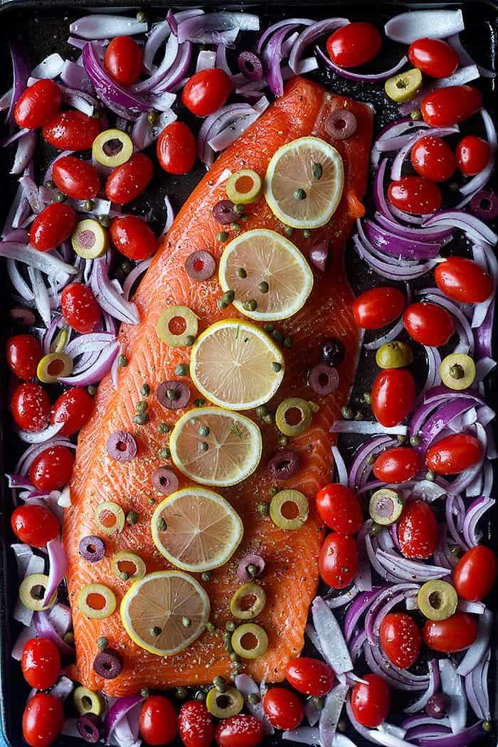 Place salmon on the baking sheet and top with lemon and capers and olives. Bake with tomatoes and onions. 