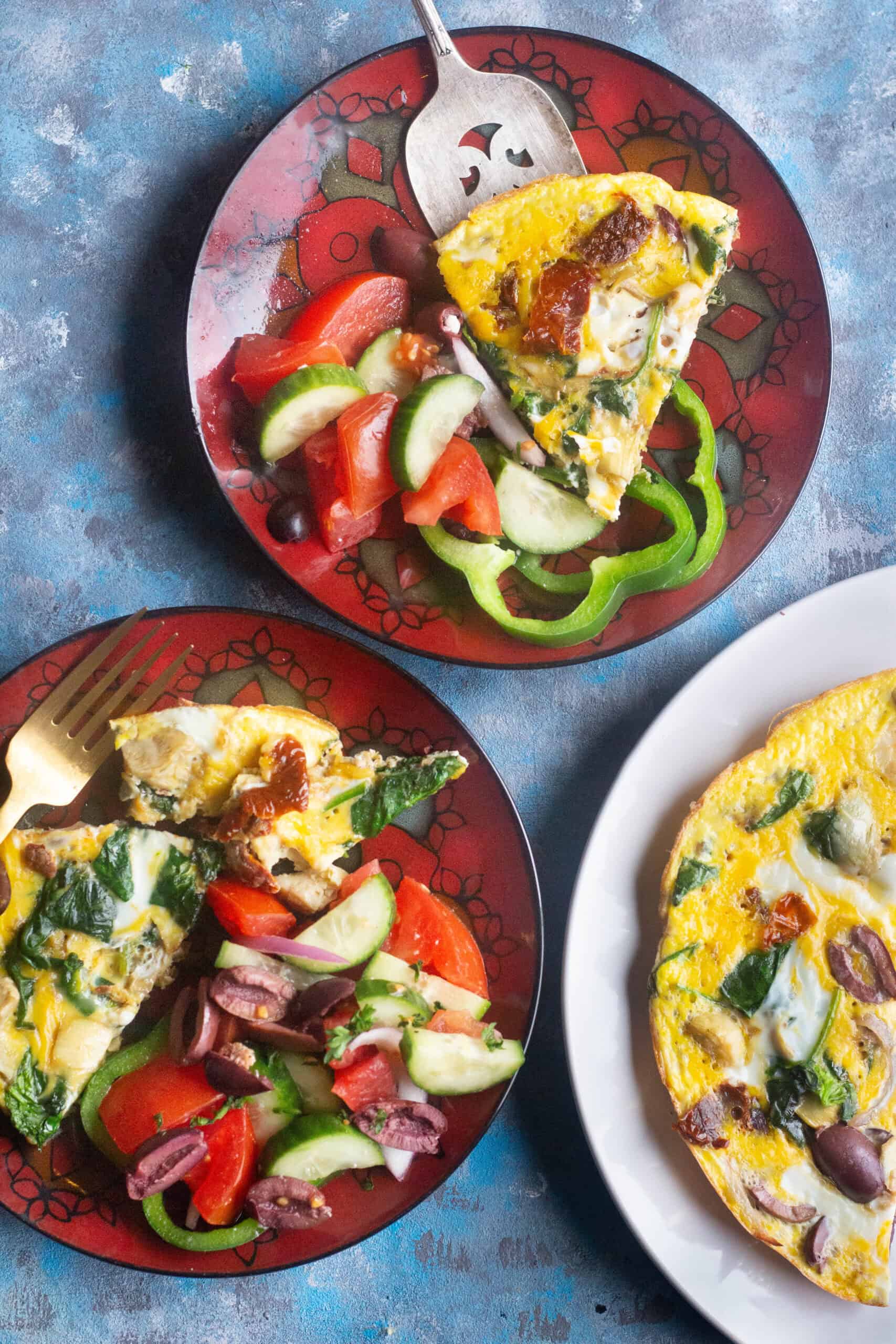 Two red plates and one white plate with omelette on a blue background.