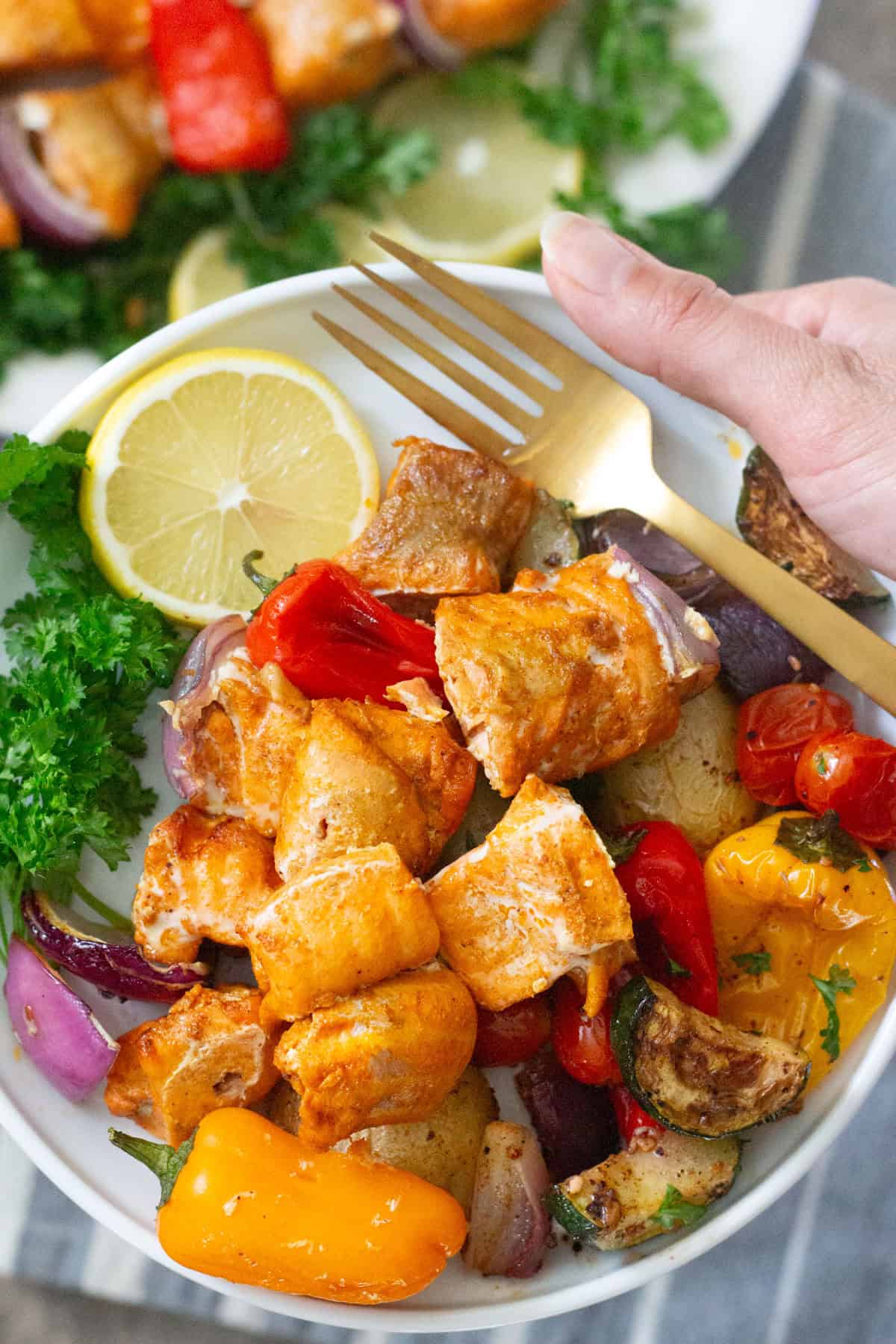 Salmon shish kabob on a plate with vegetables. 