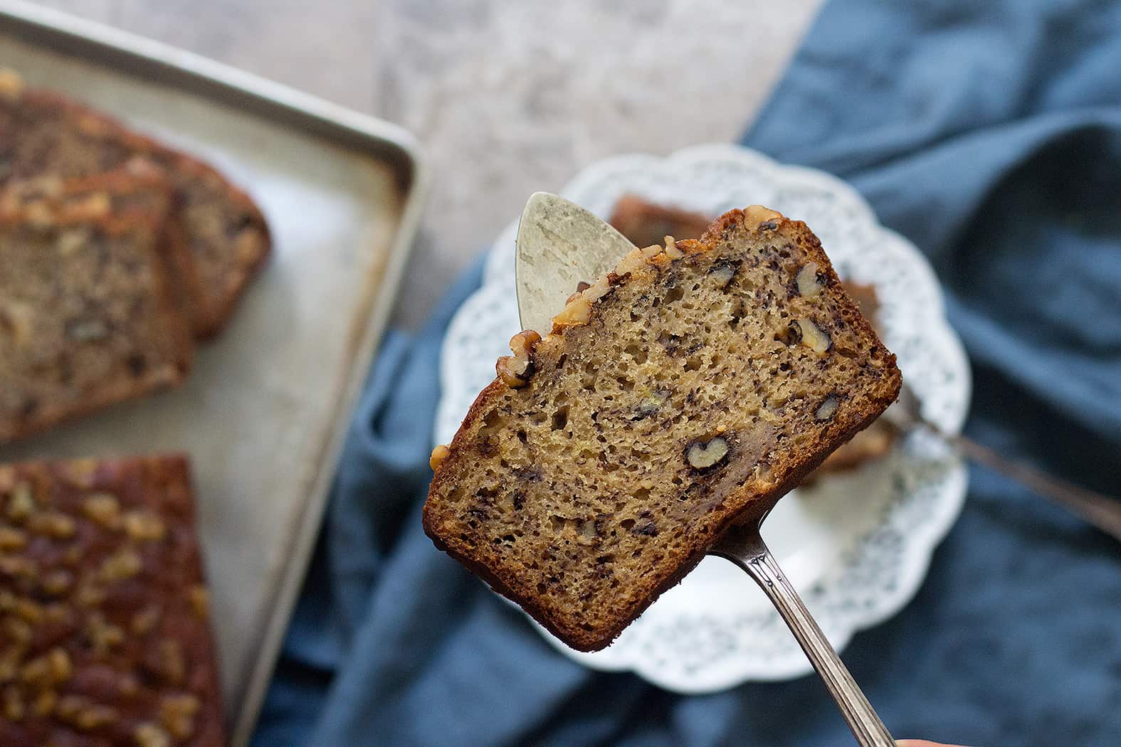 A slice of banana bread with applesauce that has walnuts in it. 