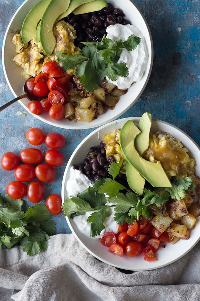 Enjoy this easy and tasty Mexican-inspired breakfast bowl made with fresh ingredients. Delicious scrambled eggs and home fries make a tasty bowl topped with fresh avocado and tomatoes.