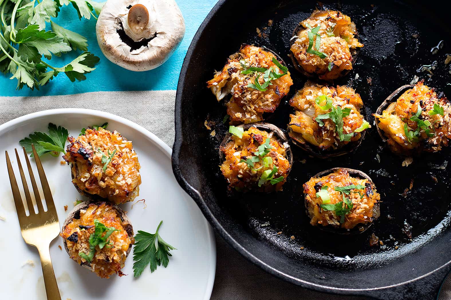 Crab stuffed mushrooms in a cast iron skillet and on a white plate.