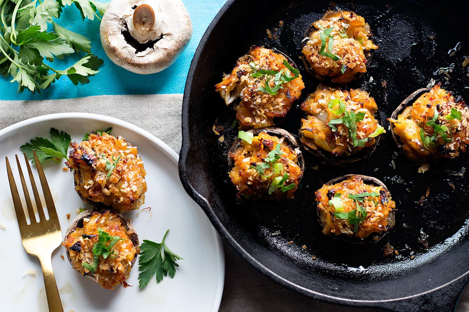 Crab stuffed mushrooms in a cast iron skillet and on a white plate. 