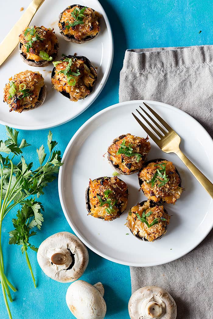 Baked stuffed mushrooms on two white plates. 