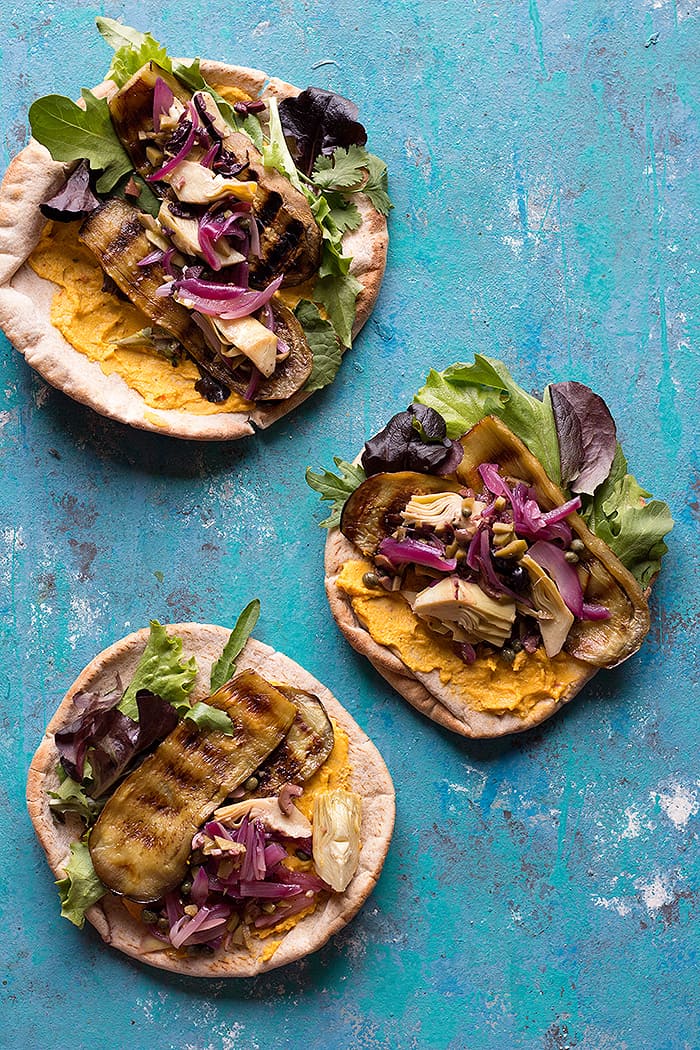 Three pita breads filled with grilled eggplant, greens, onion and hummus. 