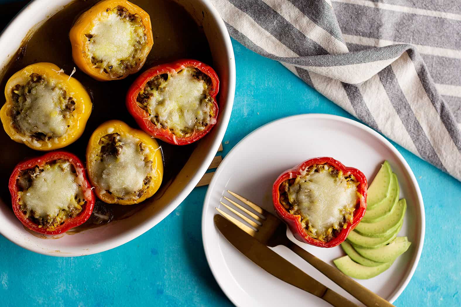 Stuffed peppers Mexican style. One on a plate and five in a serving dish. 