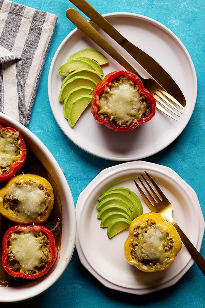 Serve mexican stuffed bell peppers with avocado on plates. 