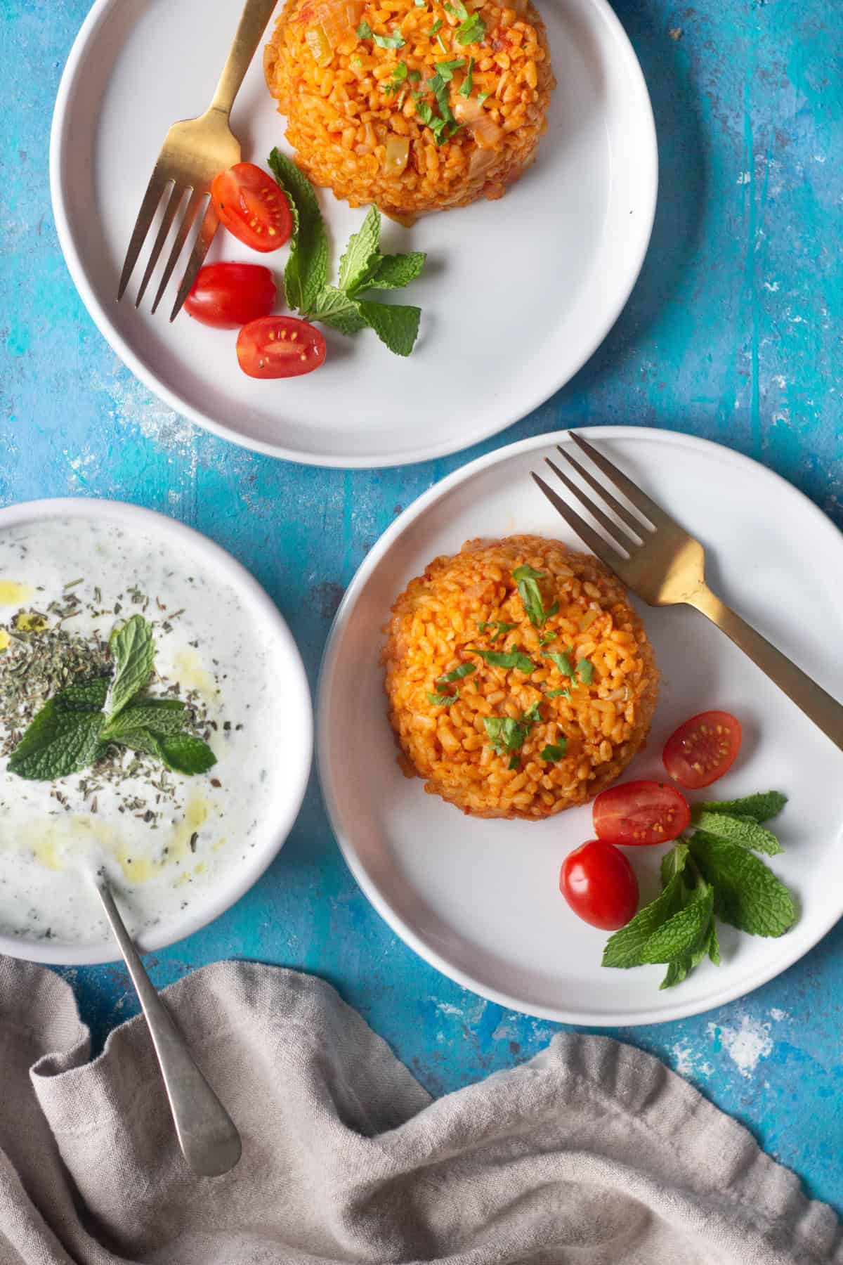 Two plates of food with yogurt and cucumber.