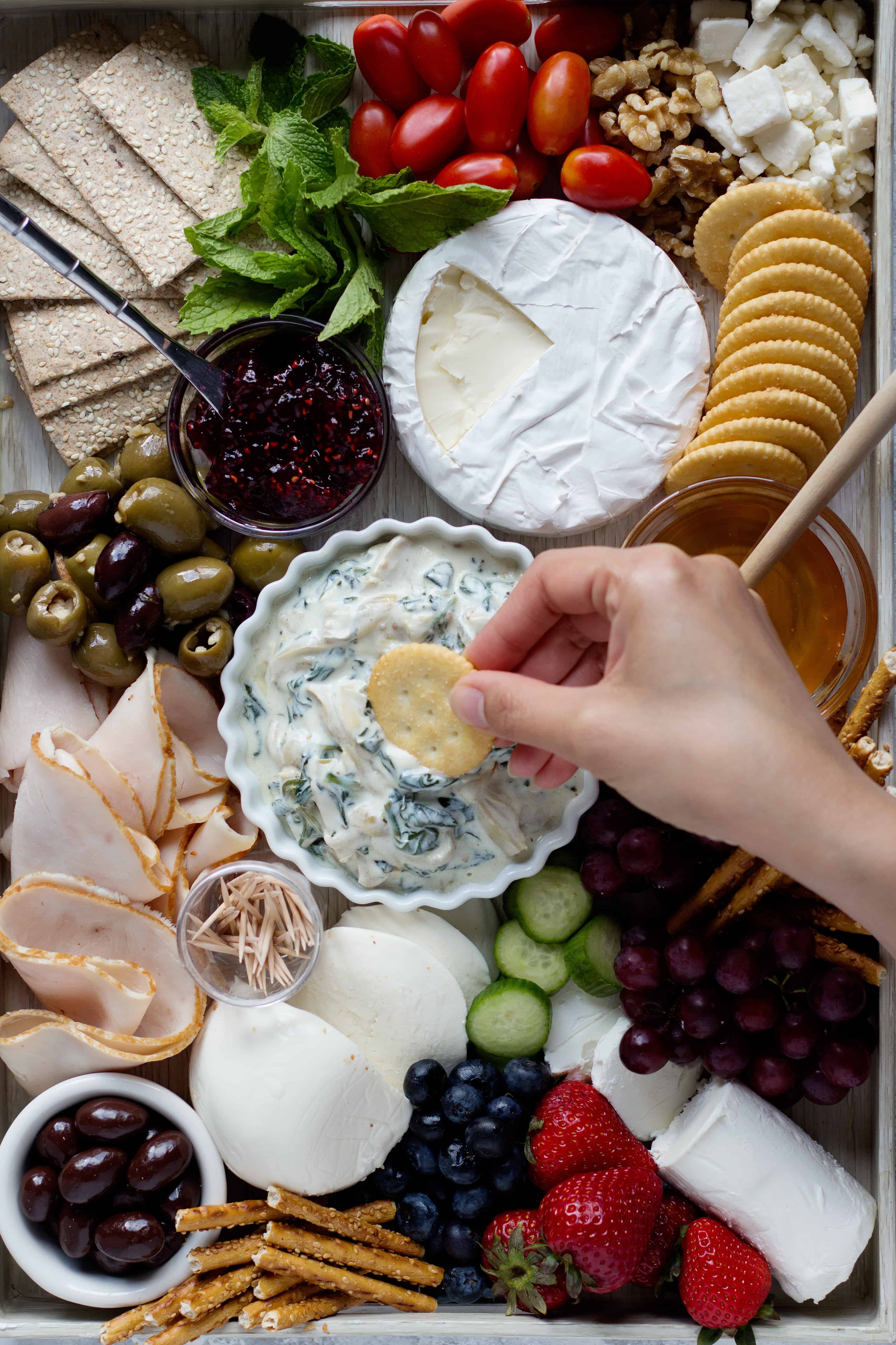 Dip crackers into a spinach artichoke dip with some olives and cheese. 