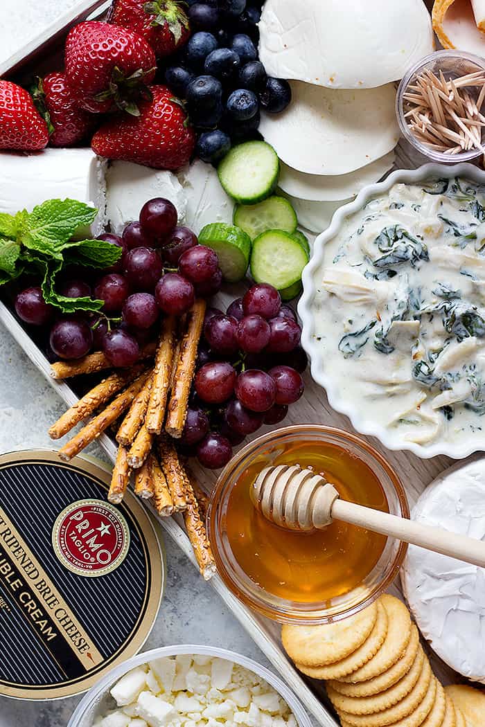 grapes, strawberries and cheese served with a cold spinach dip on a board