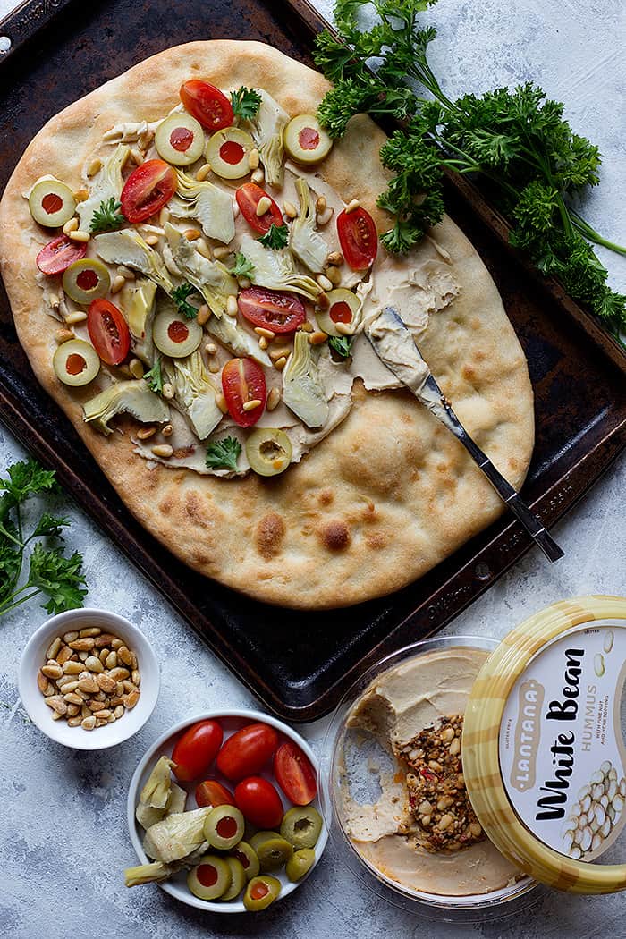 Top the flatbread with hummus, olives and tomatoes.