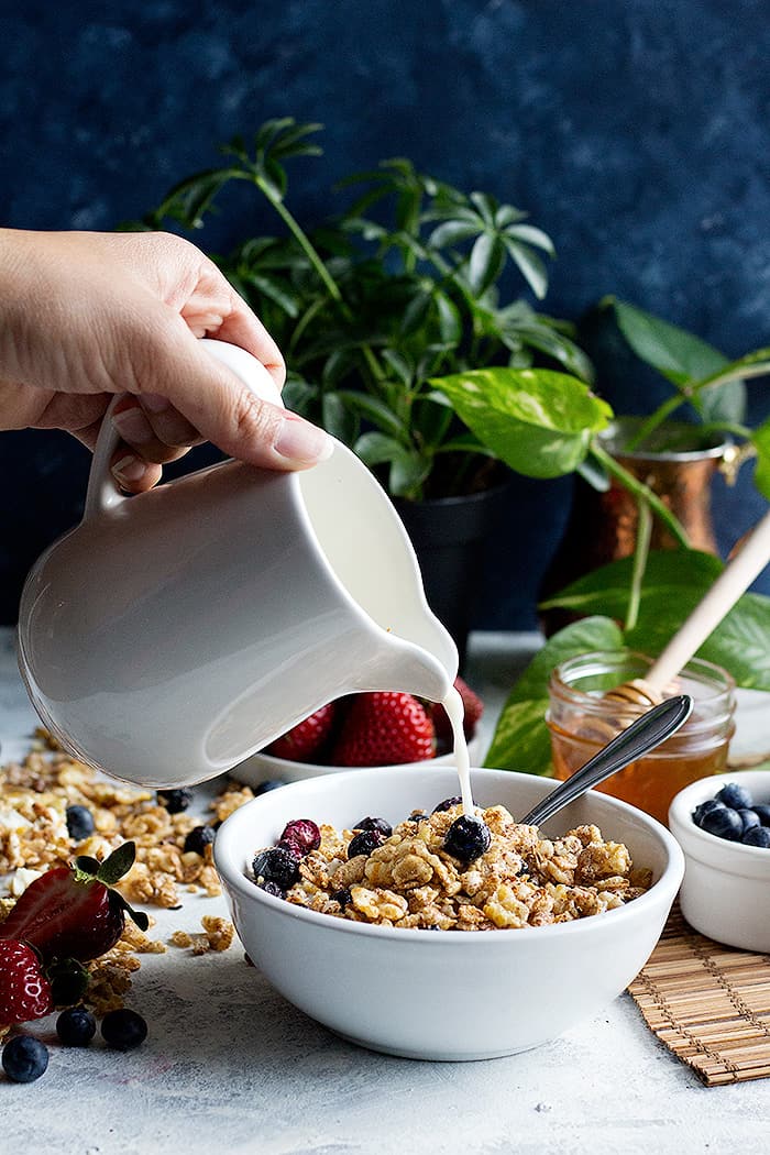 milk pour into the cereal with a background of plants and fruit. 