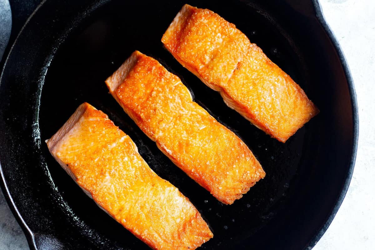 crispy salmon fillets in a pan to make orange glazed salmon recipe.