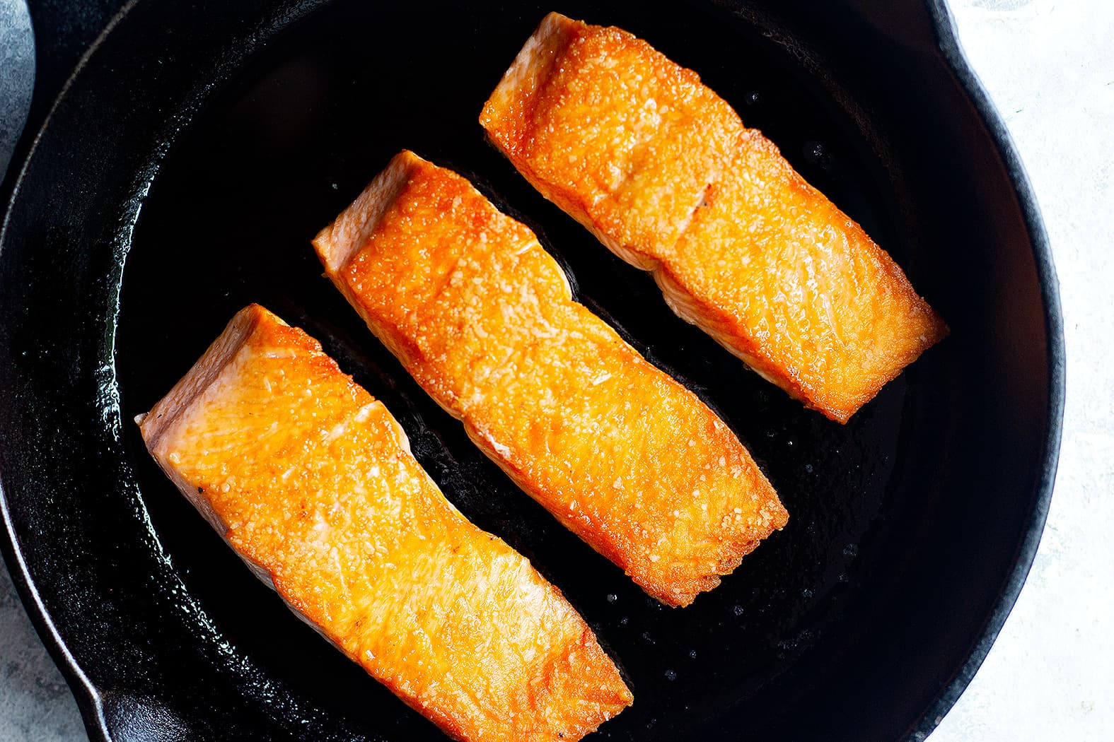 crispy salmon fillets in a pan to make orange glazed salmon recipe. 