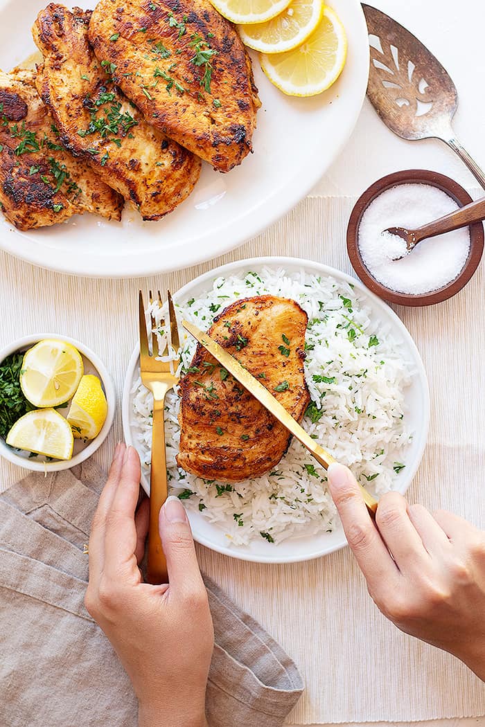 two plates of garlic lemon chicken with herb rice. 