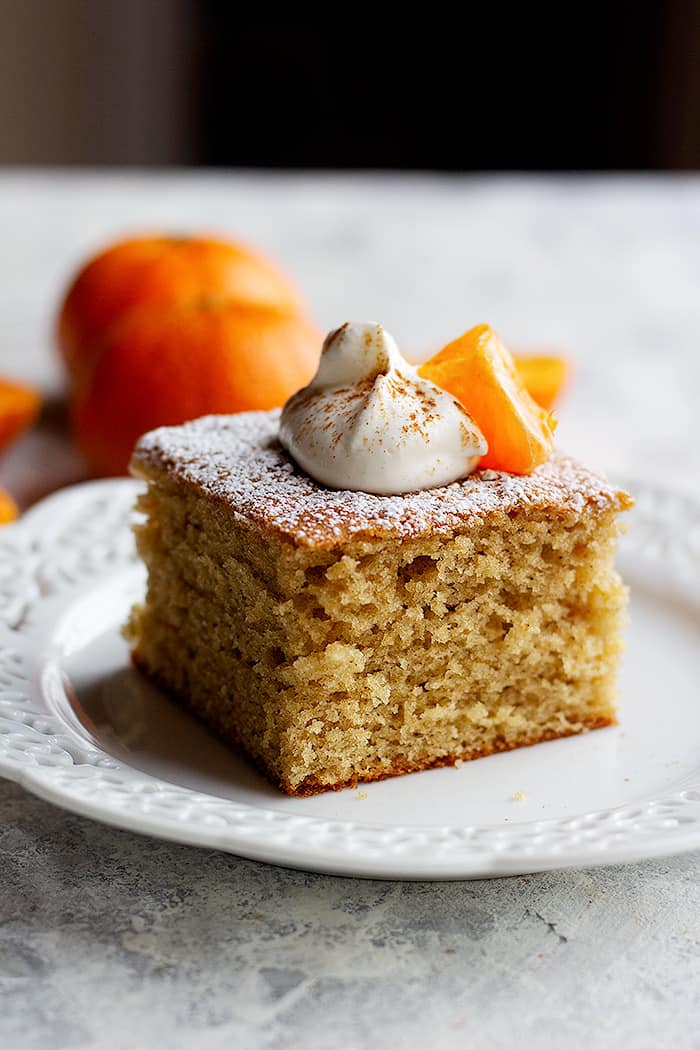 A slice of ginger spice cake topped with whipped cream and a clementine