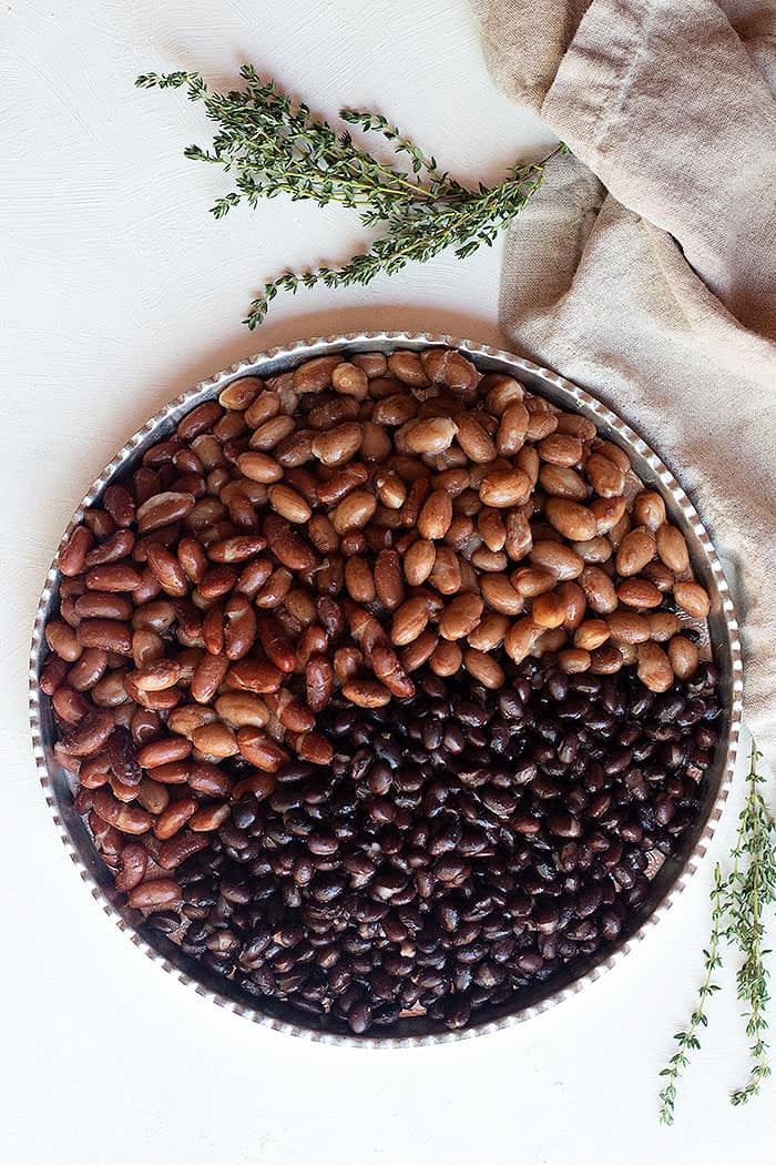 A serving tray with three types of beans, red kidney beans, pinto beans and black beans. 