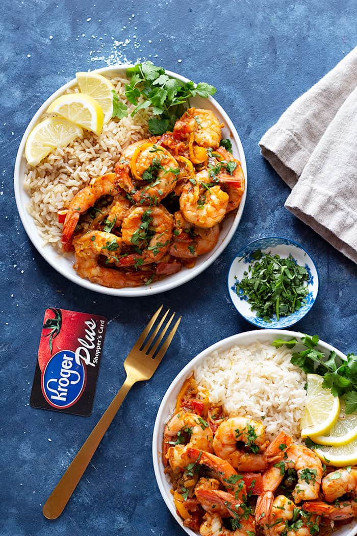 Two plates of shrimp and rice topped with lemon and parsley. 