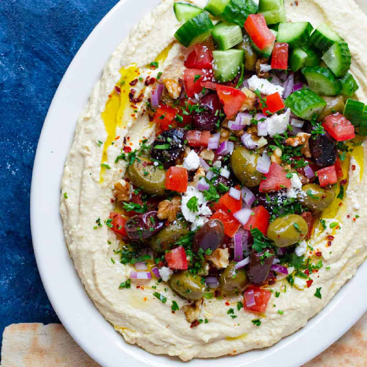 This loaded hummus recipe with all the fixings is ready in 15 minutes! Creamy hummus is topped with delicious toppings and served with pita!
