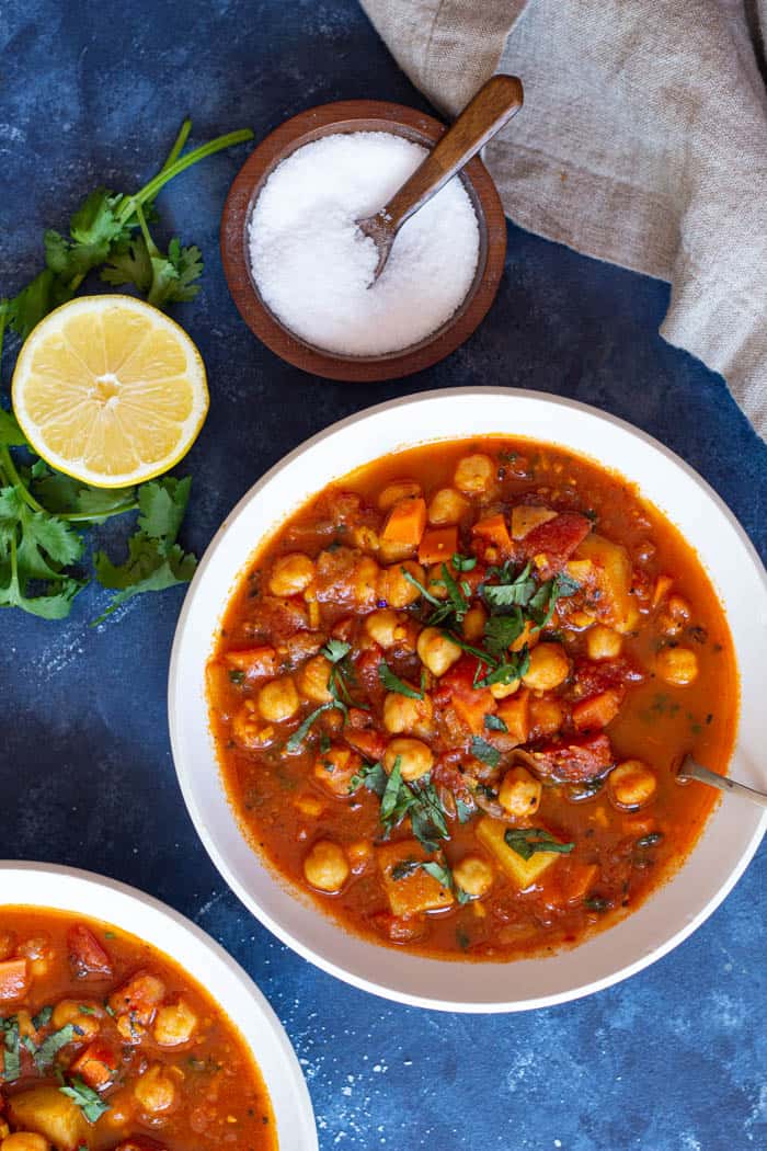 A bowl of Moroccan chickpea stew served with lemon juice and topped with parsley.