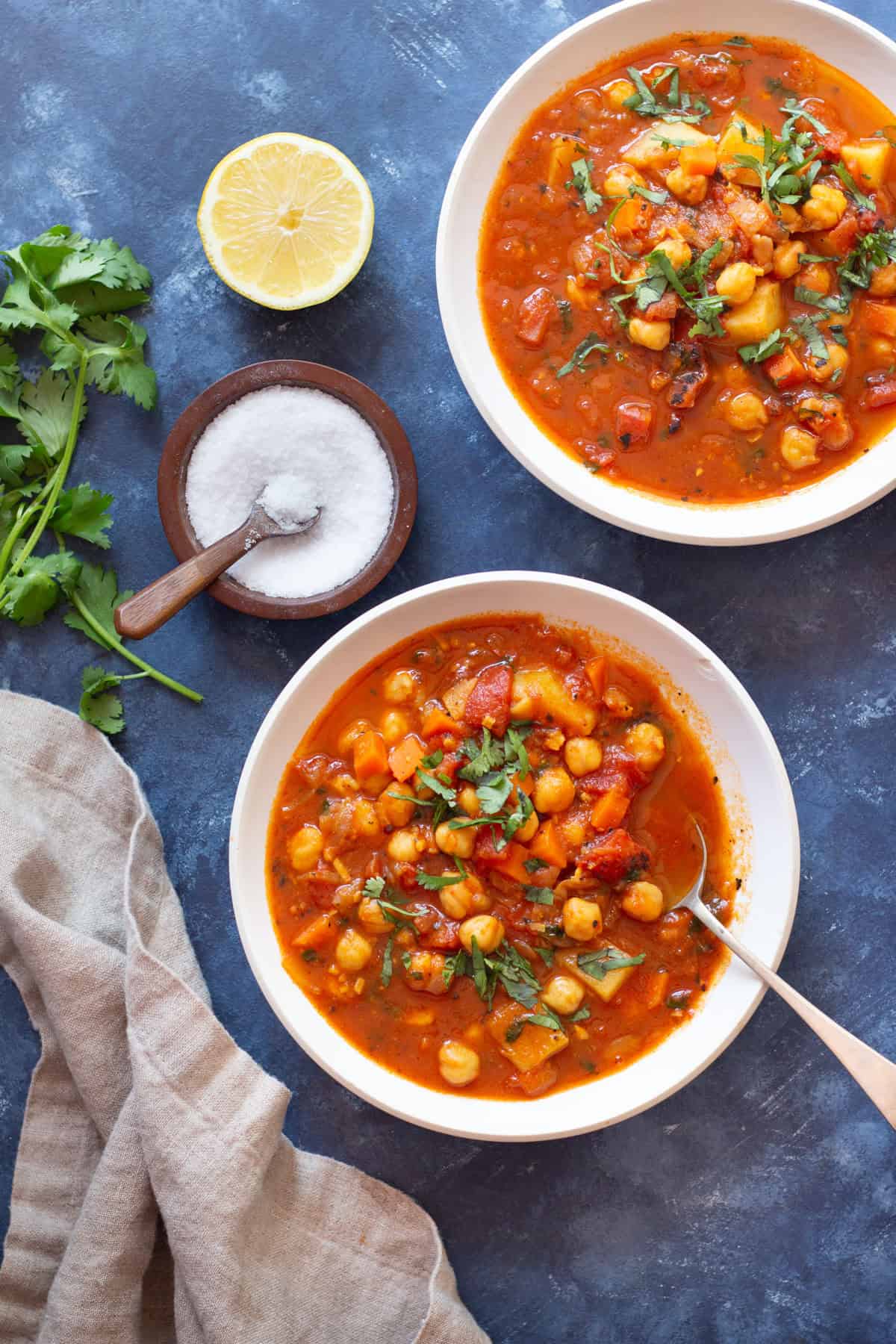 A bowl of Moroccan chickpea stew served with lemon juice and topped with parsley.