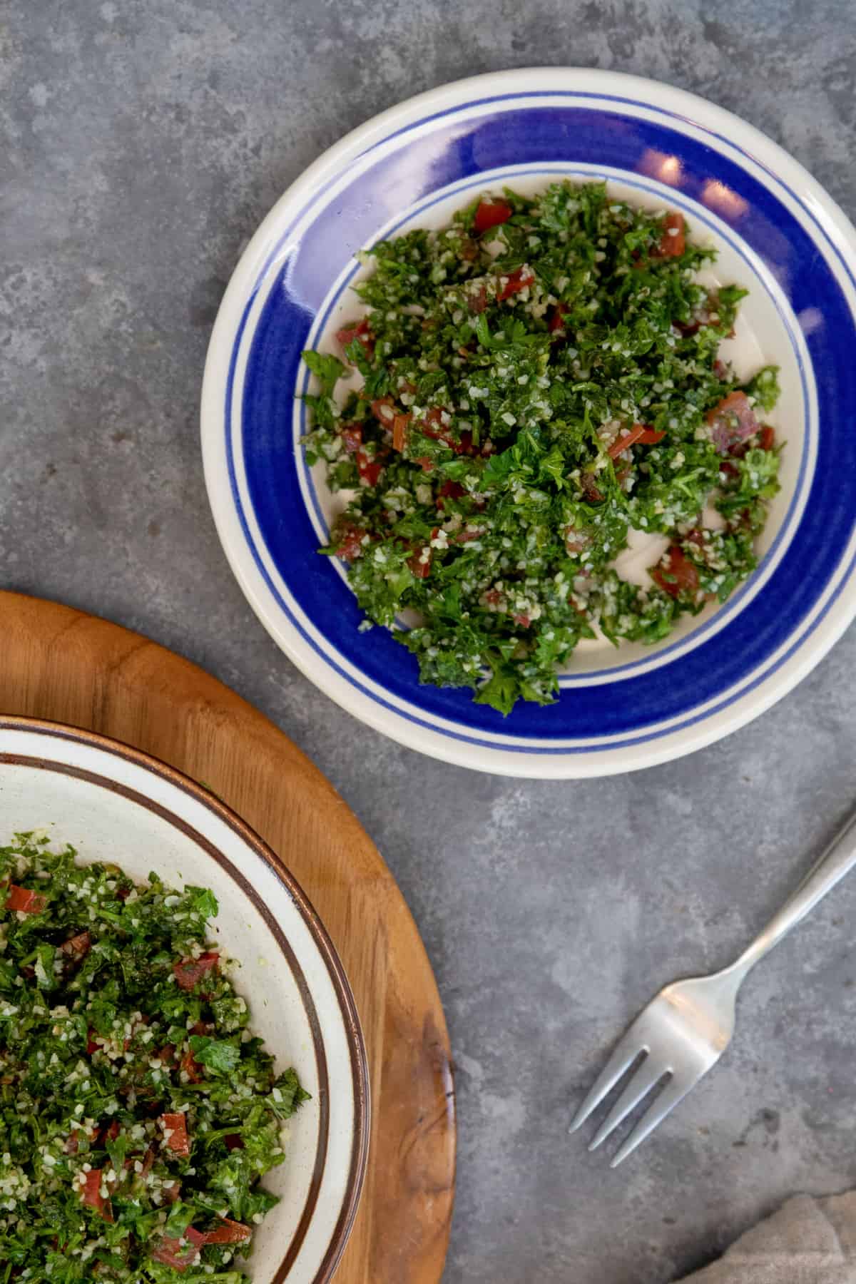 tabbouleh in a white a blue plate on a grey background.