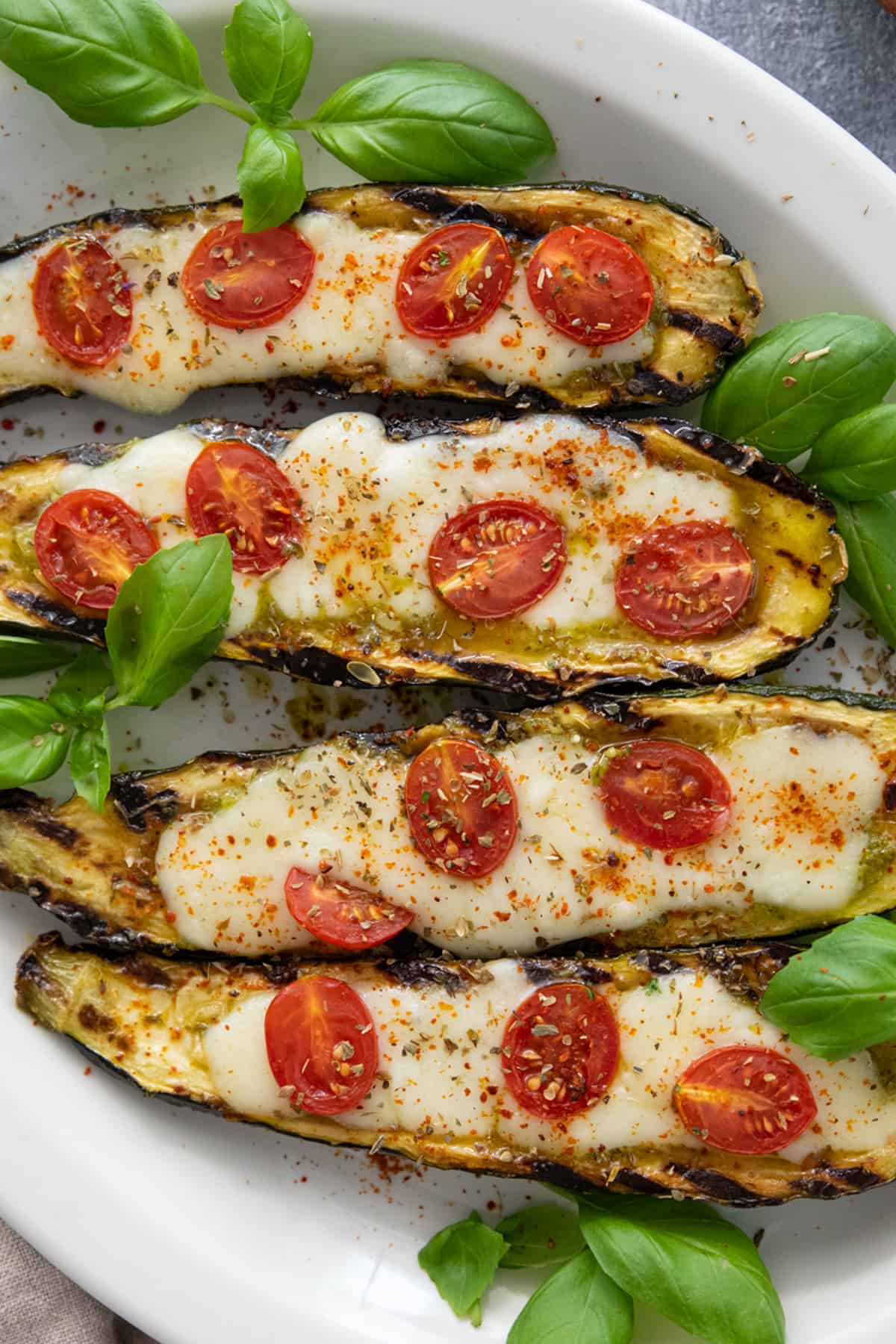 Grilled caprese style stuffed zucchini boats in a platter. 