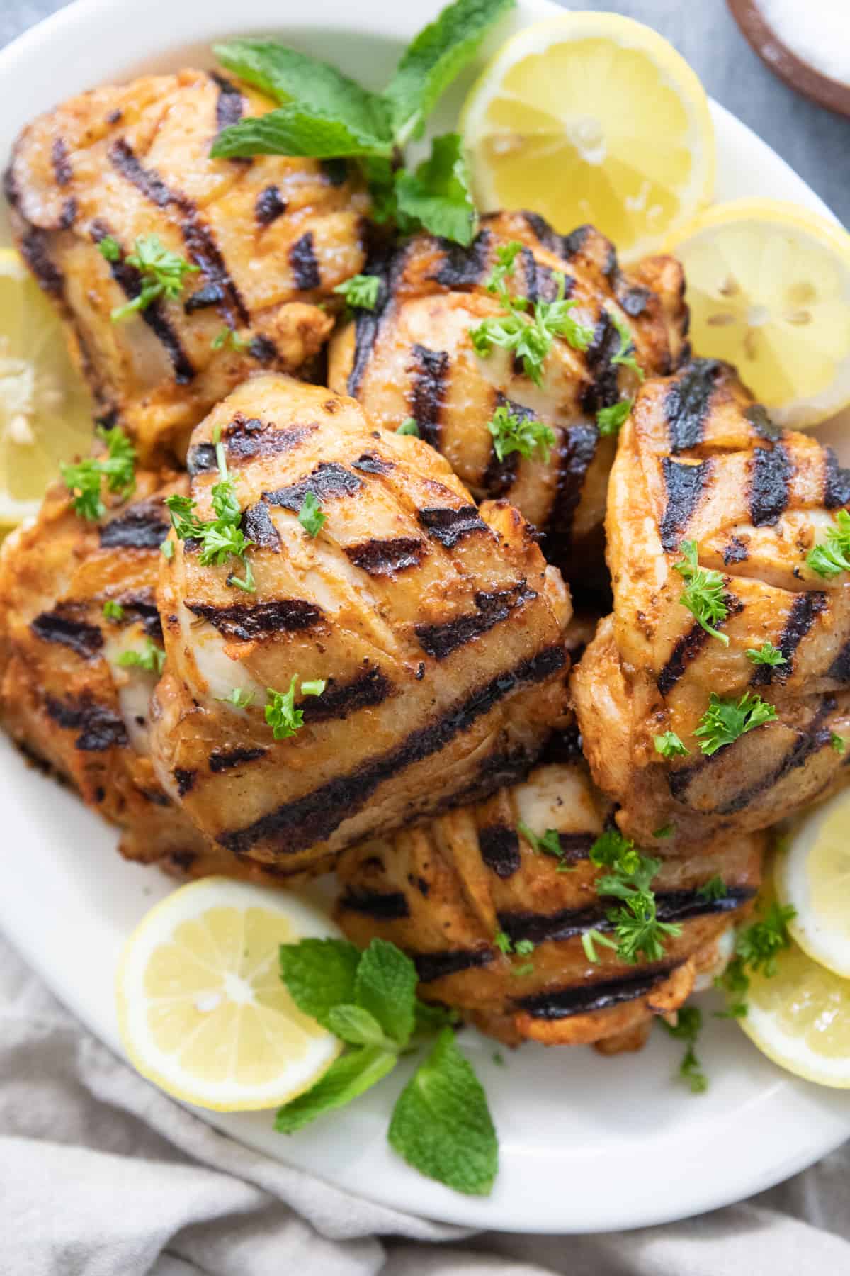 Grilled chicken thighs on a white platter. 