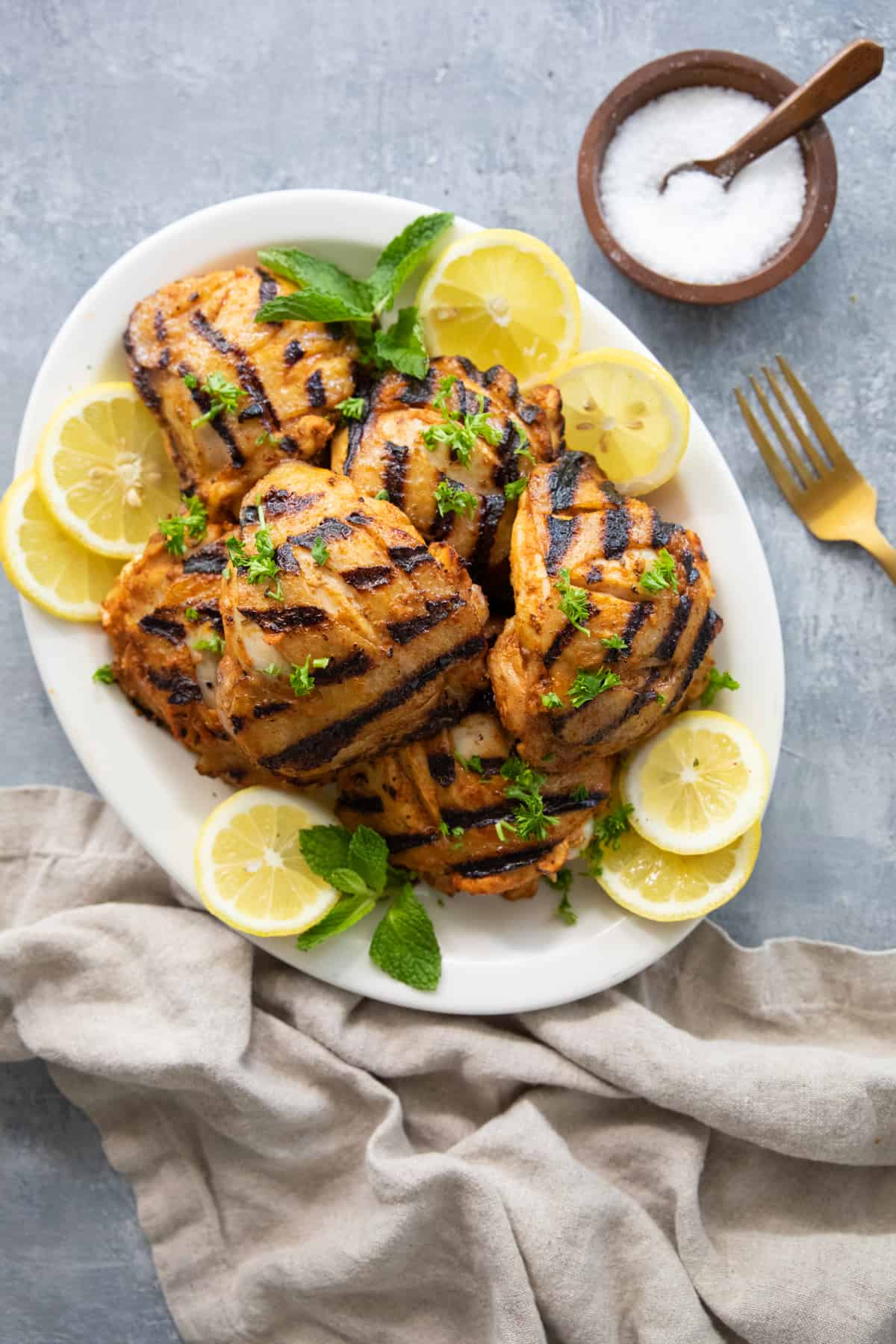 A platter of grilled chicken on a grey surface. 