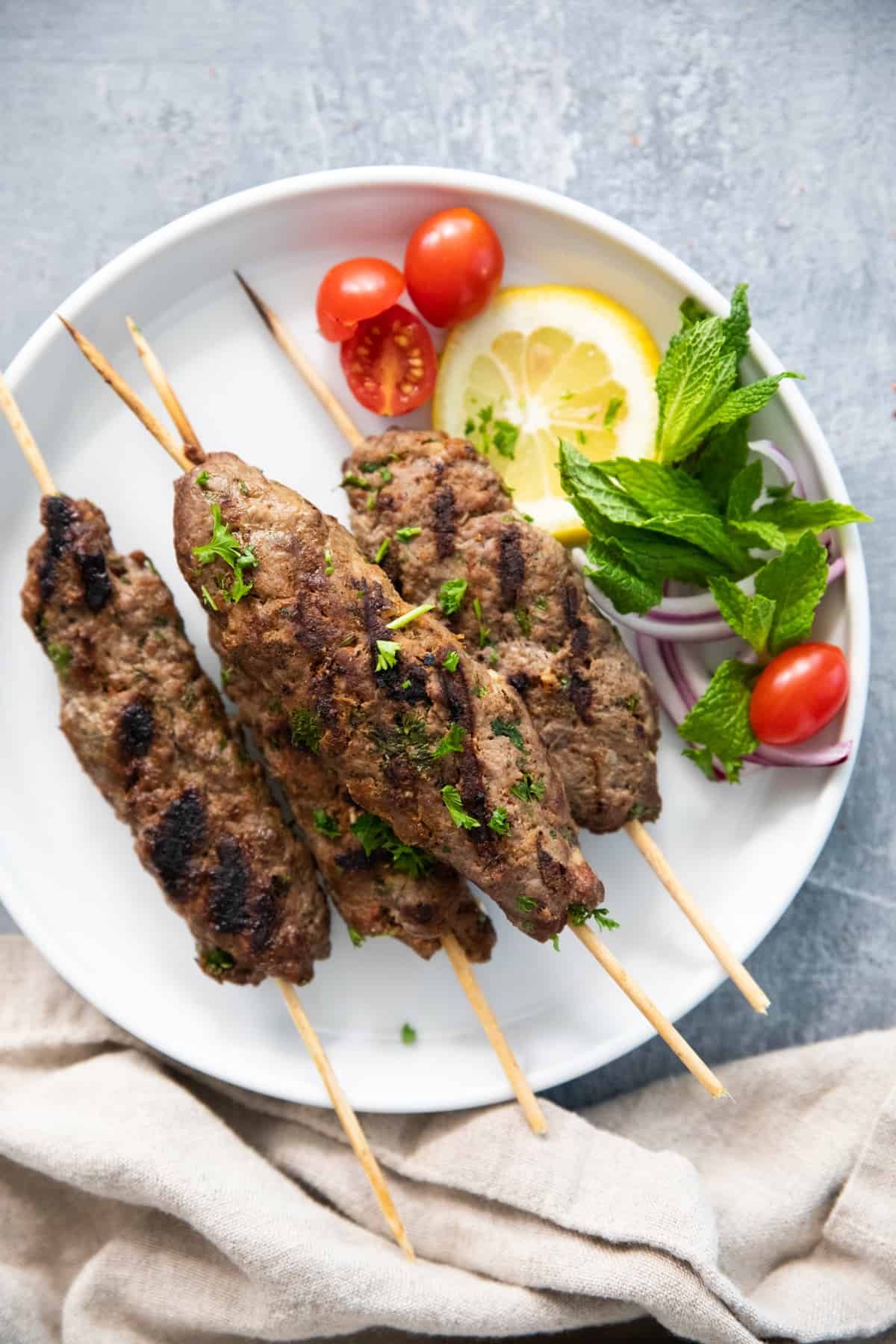 A few grilled beef skewers on a white plate. 